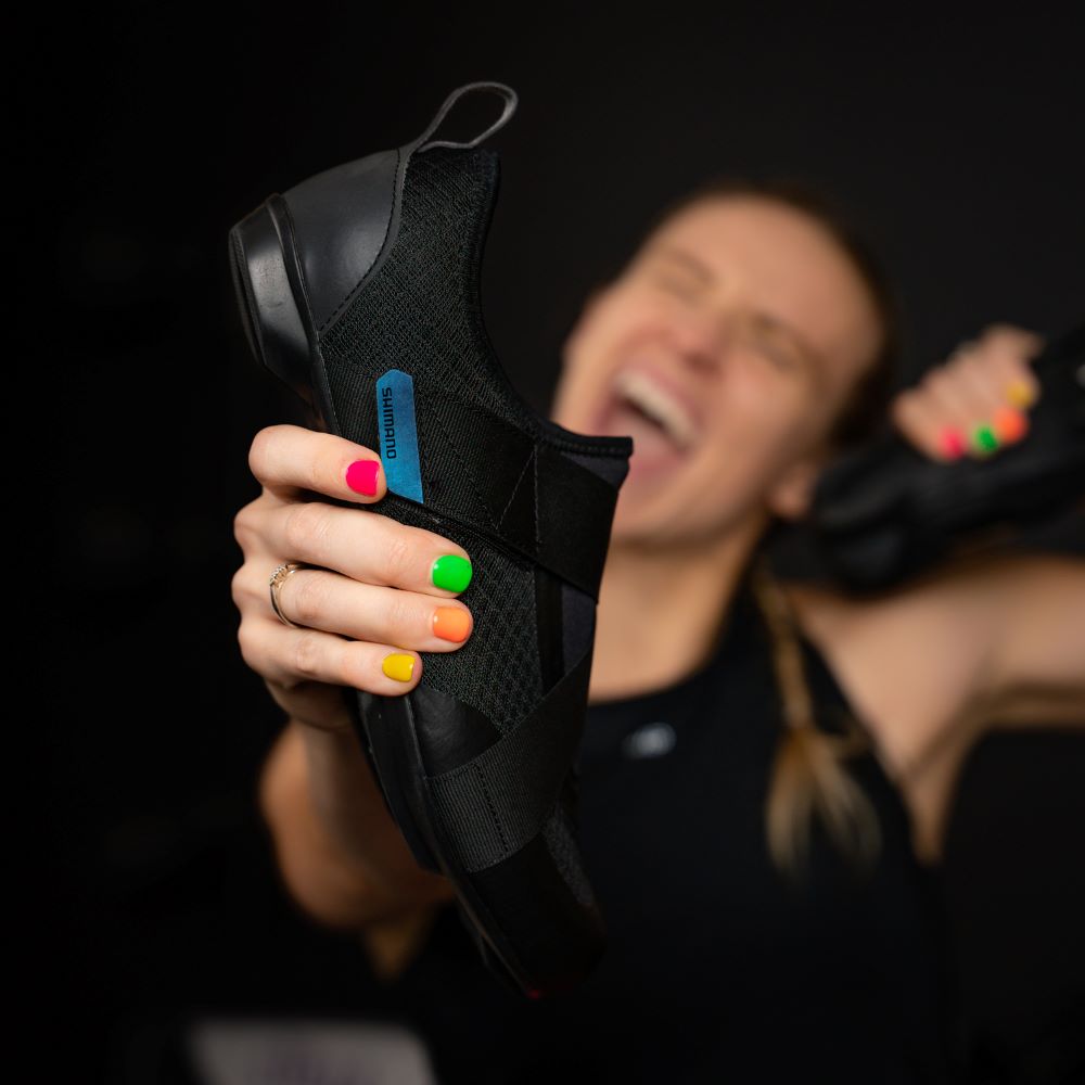 Blac Shoe being held by Kaleigh Cohen. She has multi colored nails and is smiling in background.